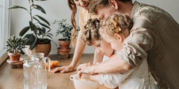 Husband and wife cook in the kitchen with their children