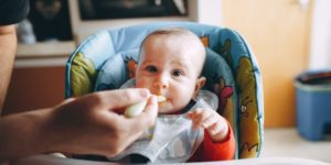 A baby in a stroller being fed