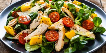 Caesar salad - vegetable salad with roast chicken meat on wooden background