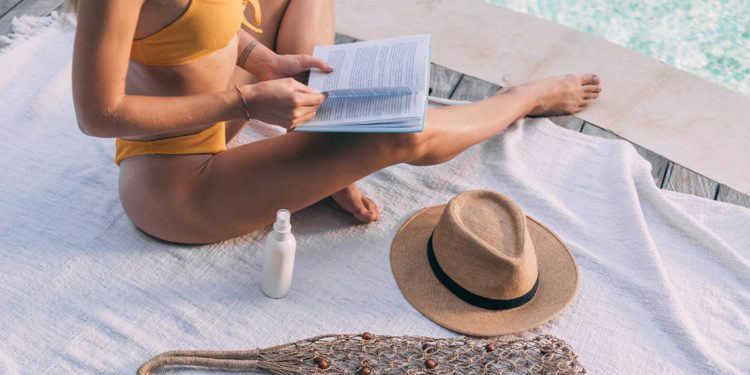 Woman in Yellow Bikini Wearing Brown Sun Hat Reading Book