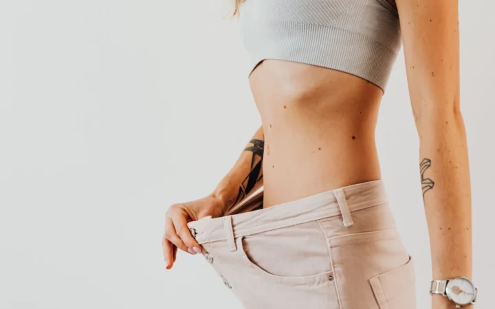 Close-up of a woman in oversized jeans symbolizing weight loss in a studio setting.