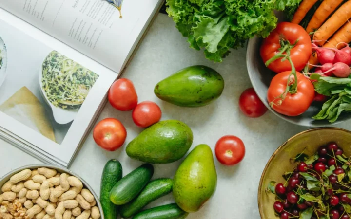 Appetizing display of fresh fruits and vegetables with a cookbook, perfect for healthy recipes.