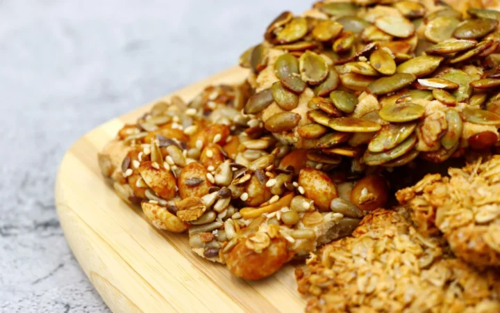Close-up of various healthy homemade mixed nut and seed snacks on a wooden board.