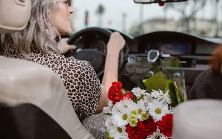 Woman driving, holding a bouquet of colorful flowers in a car.