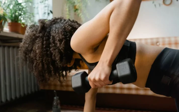 African American woman working out with dumbbells in an indoor setting, promoting a healthy lifestyle.