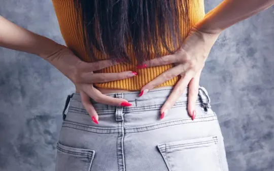 A woman pressing both hands into her lower back