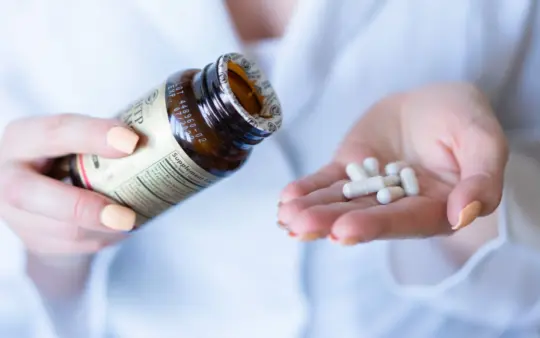 Close-up shot of hands holding a medicine bottle and pills, with a focus on healthcare and medication usage.