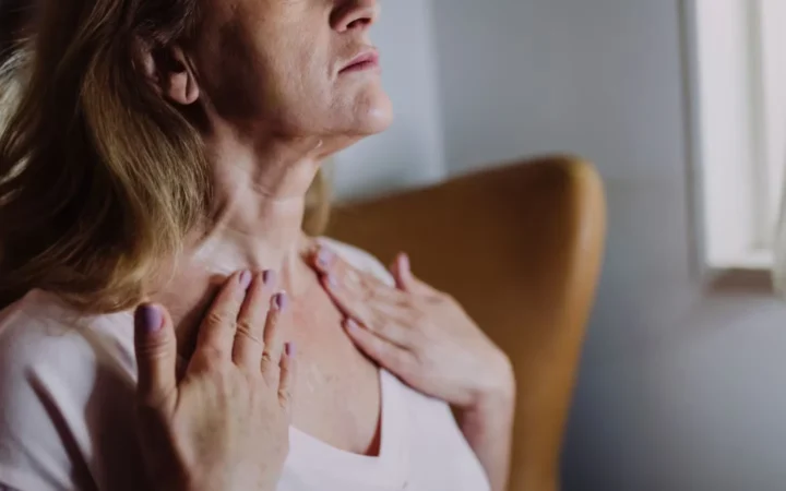 Mature woman gently massaging moisturizer into her neck, highlighting skincare routine and self-care.