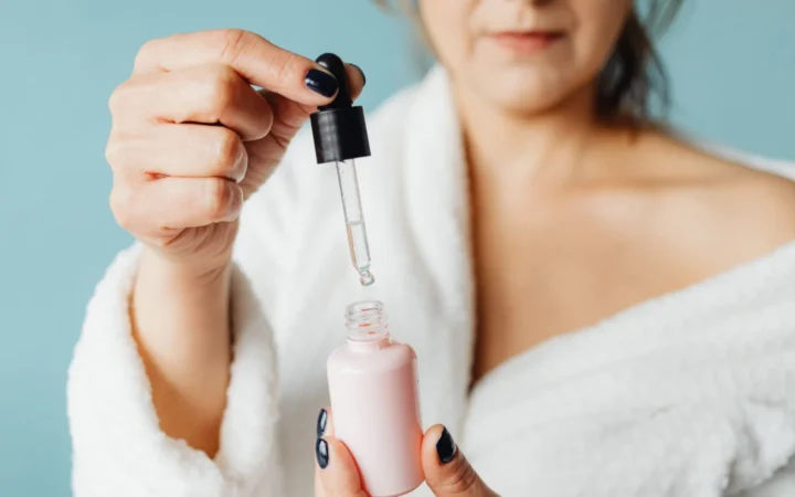 Close-up of an adult woman applying serum with a pipette indoors.