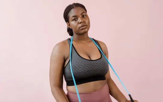 Young woman in stylish activewear using a resistance band during a workout session.