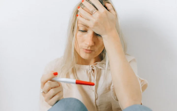Concerned woman looks at a pregnancy test, reflecting emotions of anxiety and uncertainty.