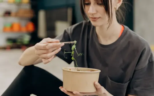 Young woman enjoying a healthy salad indoors, focusing on balanced nutrition and healthy living.
