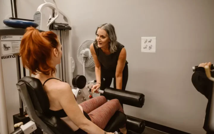 Personal trainer guiding women during a workout session in a gym setting.