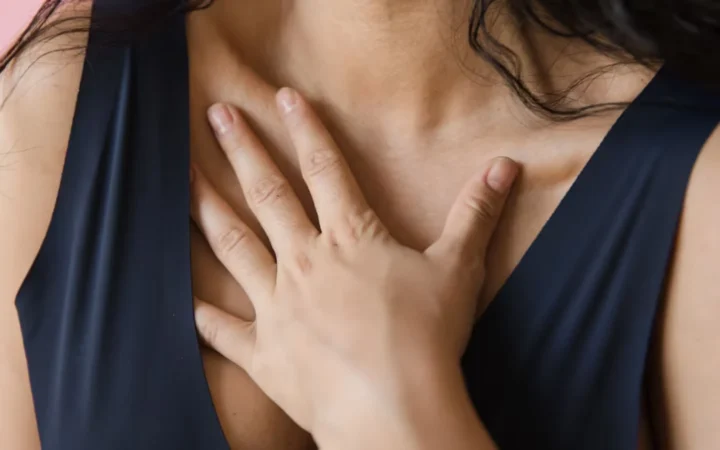A woman resting both hands on her chest, aware of her own heartbeat