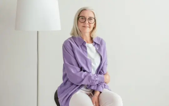Portrait of a happy senior woman with glasses and white hair, wearing casual clothing.
