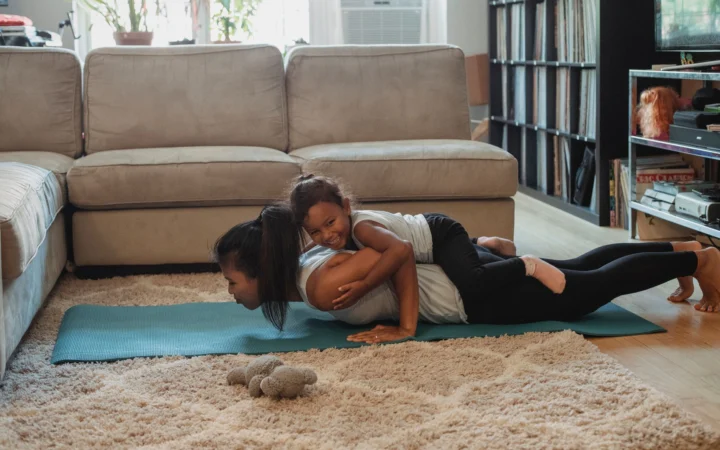 Side view of young Hispanic female athlete having fun with daughter while doing exercise