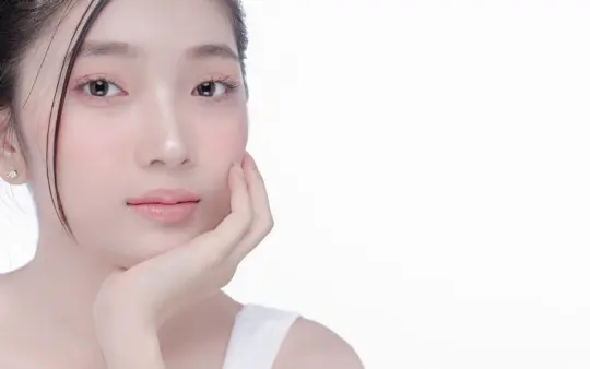 Close-up portrait of a young woman with clear skin in a studio setting, showcasing beauty and skincare.