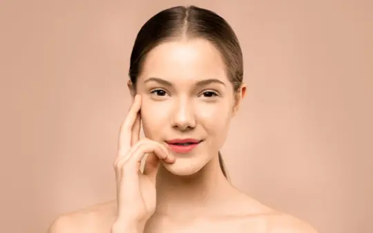 Close-up portrait of a young woman with flawless, radiant skin and a gentle smile, exuding natural beauty.