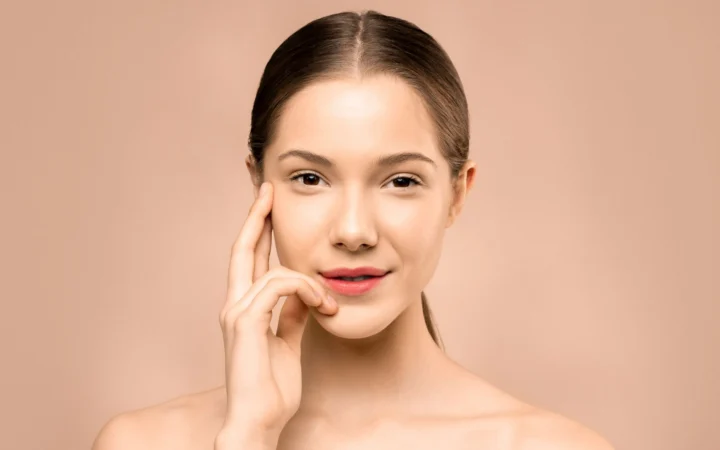 Close-up portrait of a young woman with flawless, radiant skin and a gentle smile, exuding natural beauty.