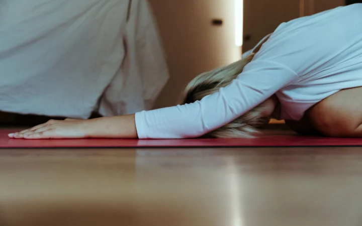 Young female practicing yoga at home wearing casual clothes and stretching body while doing extended child asana during
