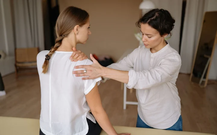 Therapist performing a shoulder massage on a woman to relieve physical tension.