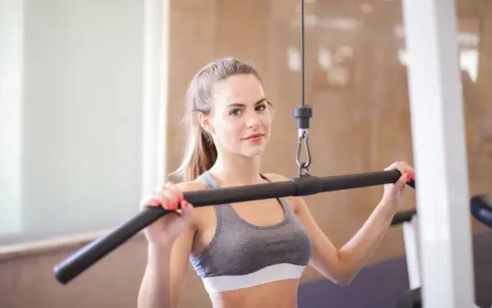 Young woman using gym equipment for strength training in a modern fitness facility.
