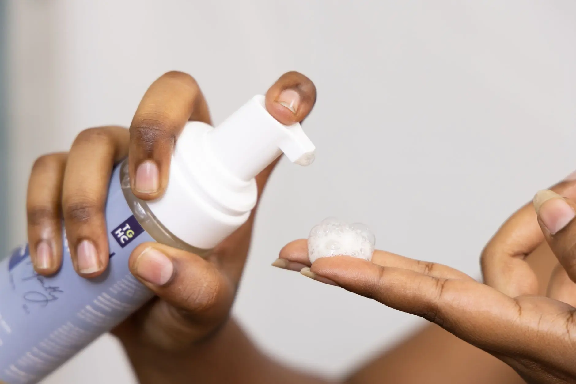 Close-up of hands dispensing soothing foaming face wash, ideal for sensitive skin care