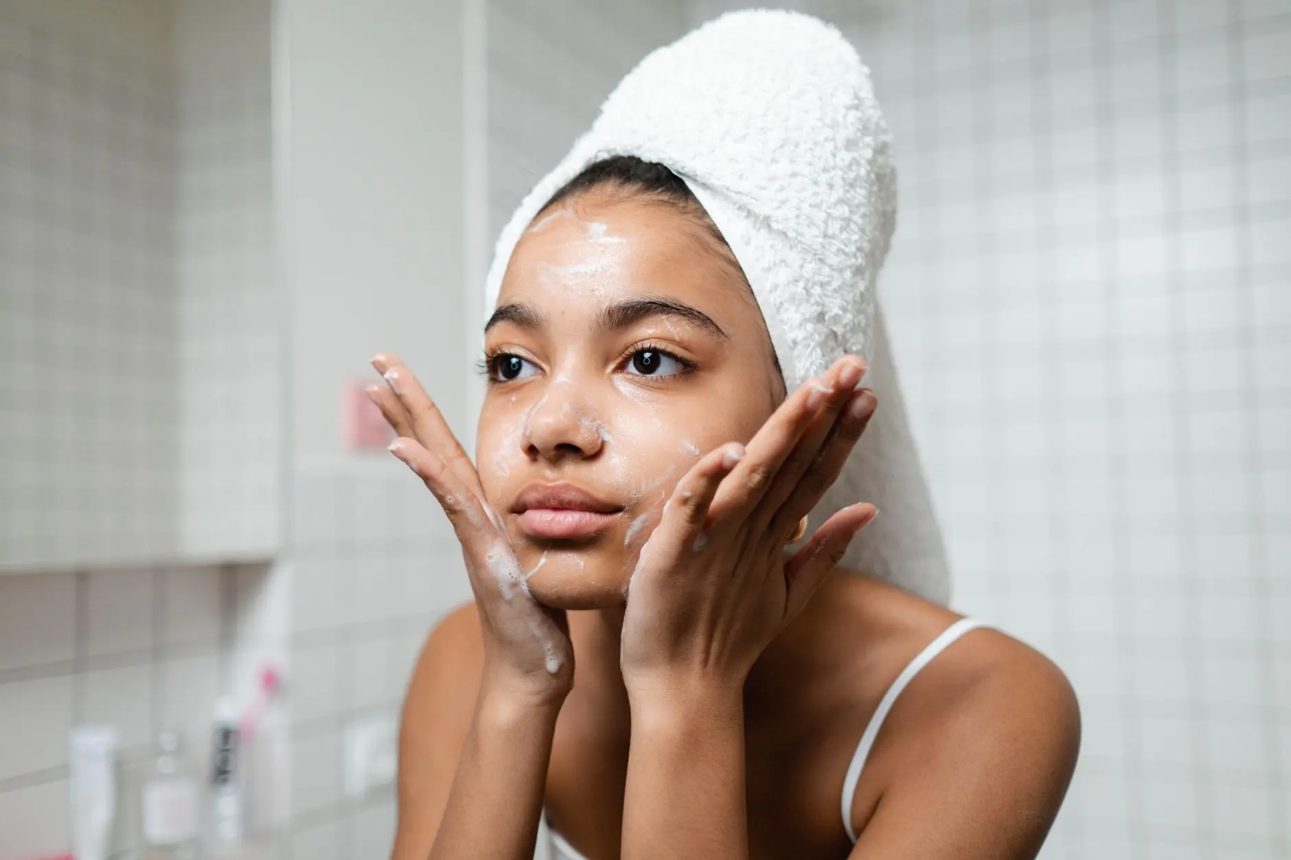 Young woman practicing skincare routine with a towel wrap indoors