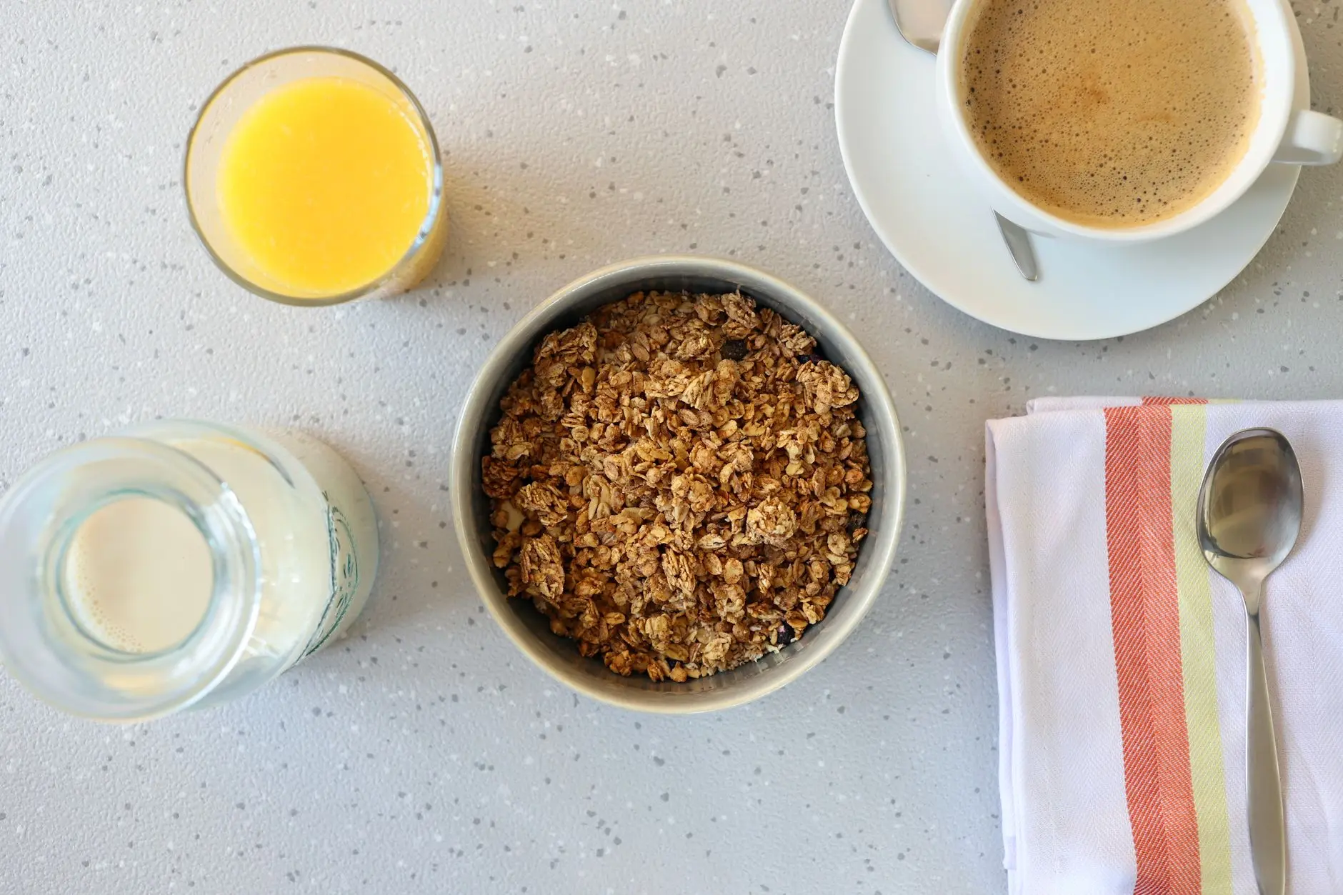Top view of a nutritious breakfast setup including granola, orange juice, and a cup of coffee