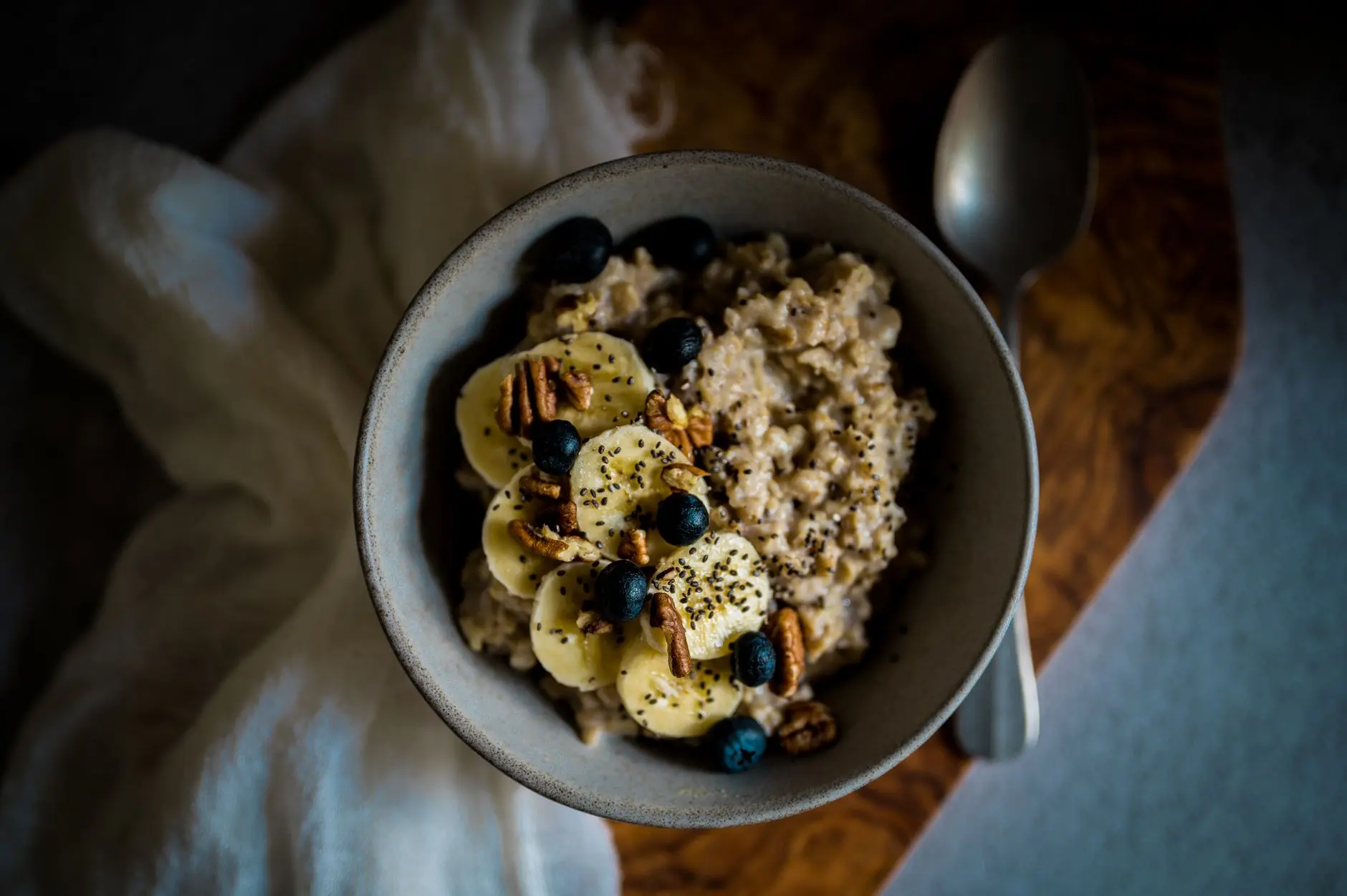 Delicious oatmeal topped with bananas, blueberries, pecans, and chia seeds in a cozy setting