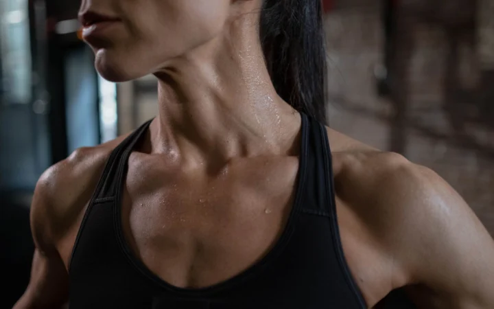 Close-up of a fit and muscular woman sweating post-workout, highlighting strength and fitness.
