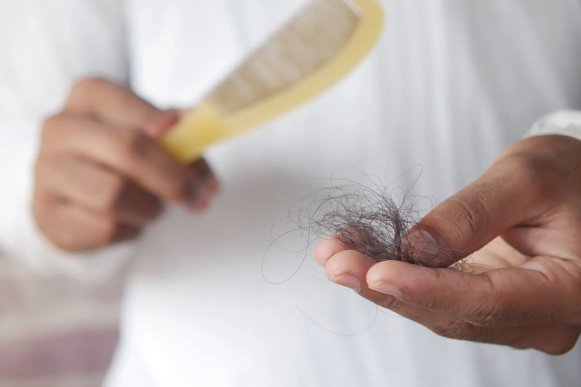 A detailed image showing hair loss with a comb in hand, symbolizing alopecia and related issues