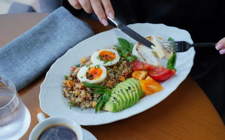 Delicious and healthy breakfast featuring avocado, eggs, and coffee served on a wooden table.