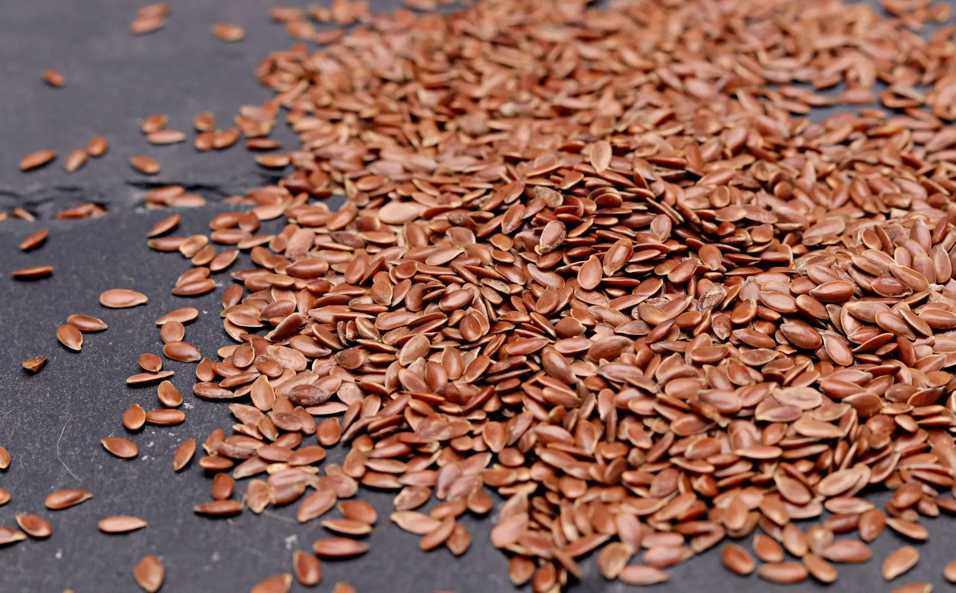 High-resolution close-up of nutritious flaxseeds scattered on a dark background, perfect for health and diet concepts