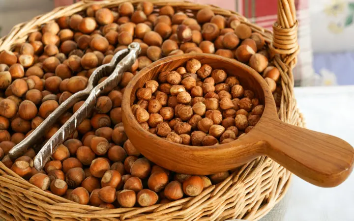 High fiber foods for acid reflux: an artistic display of hazelnuts in a wicker basket with a wooden scoop and metal tongs