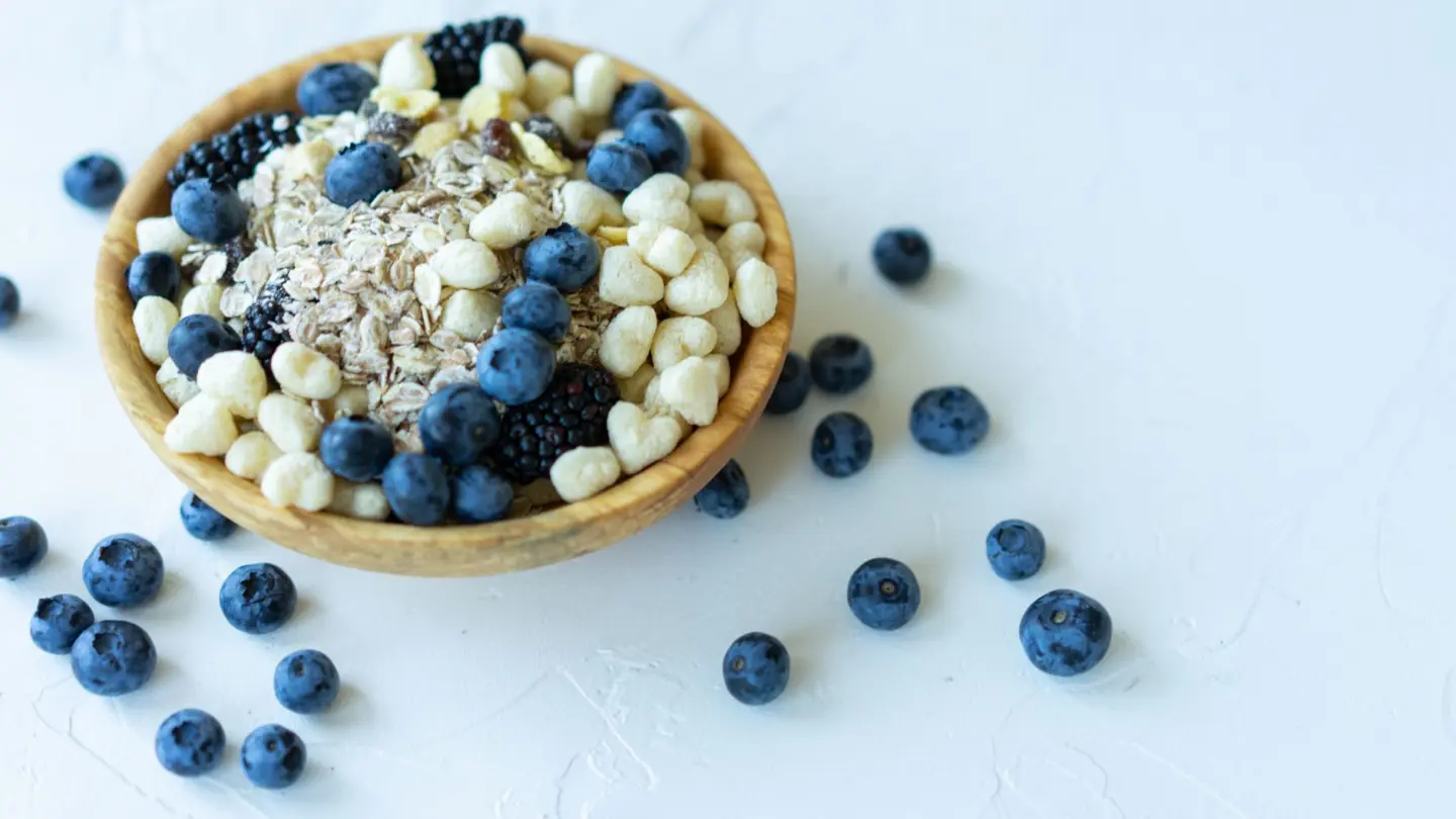 Nutrient-rich breakfast bowl with oats, blueberries, and puffed grains on a white background