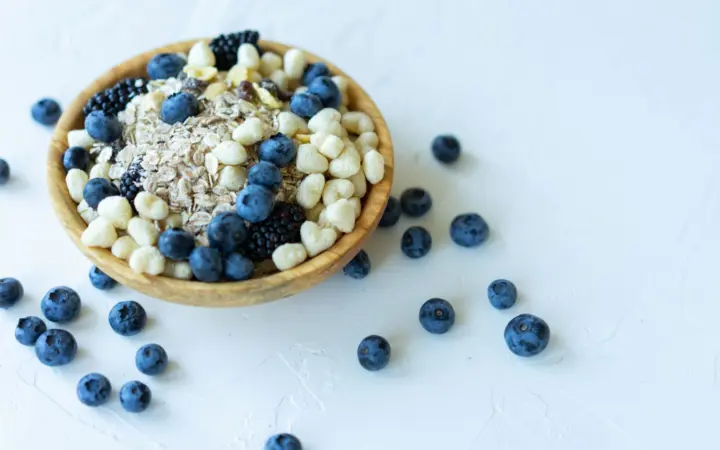 Nutrient-rich breakfast bowl with oats, blueberries, and puffed grains on a white background