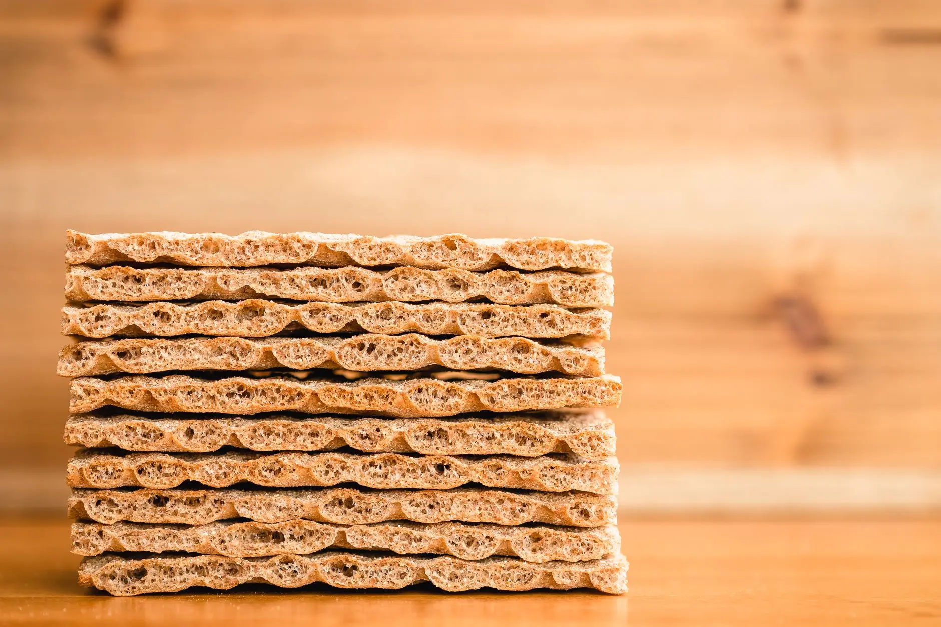 A neatly stacked pile of crispbread crackers against a wooden background