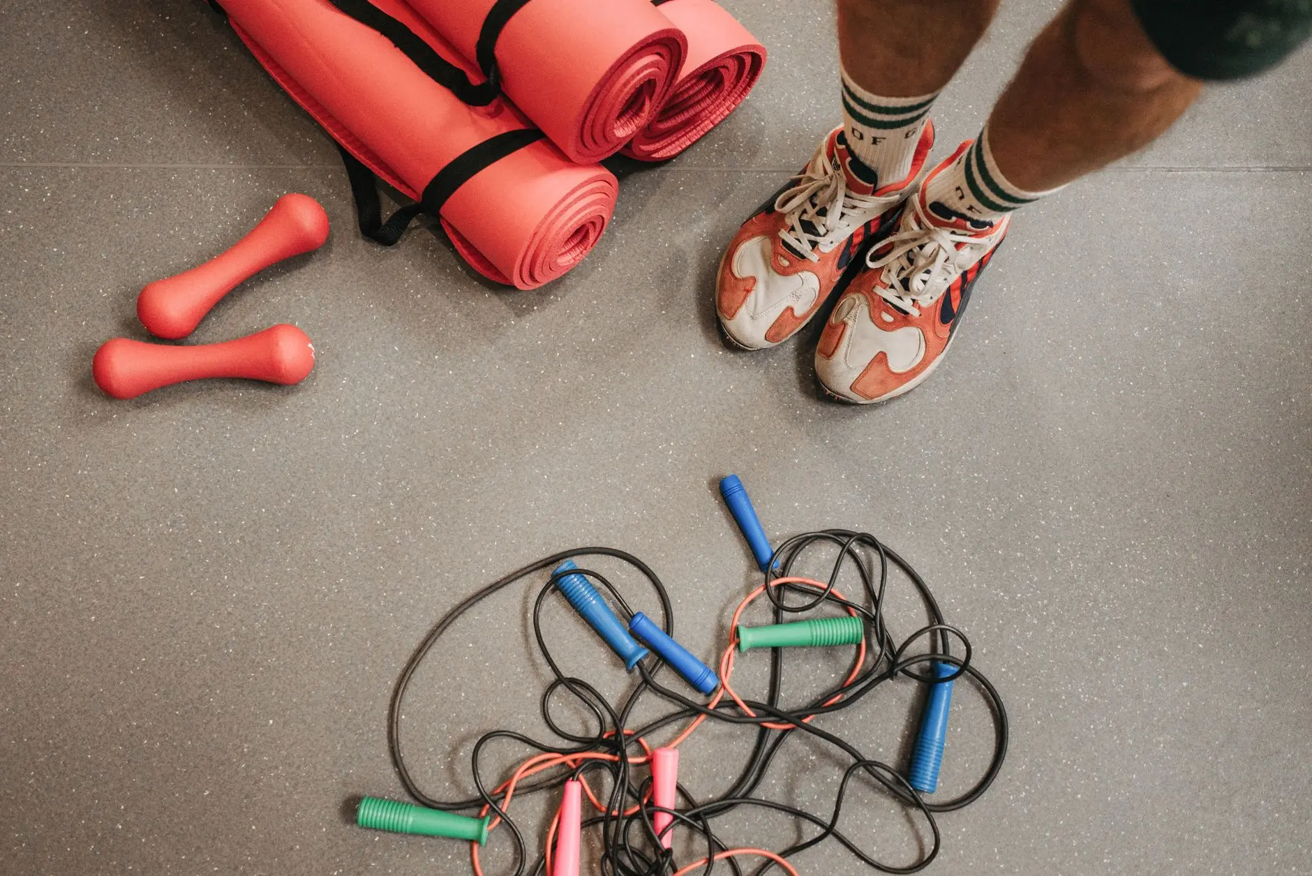 Fitness equipment including shoes, mats, weights, and skipping ropes on a gym floor