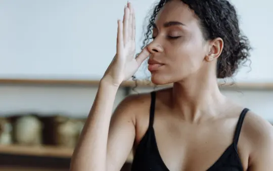 Close-up of a woman practicing yoga breathing techniques indoors, focusing on relaxation.