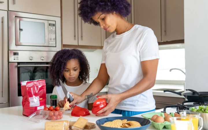 Mother and daughter cooking together, preparing a healthy meal in a modern kitchen.