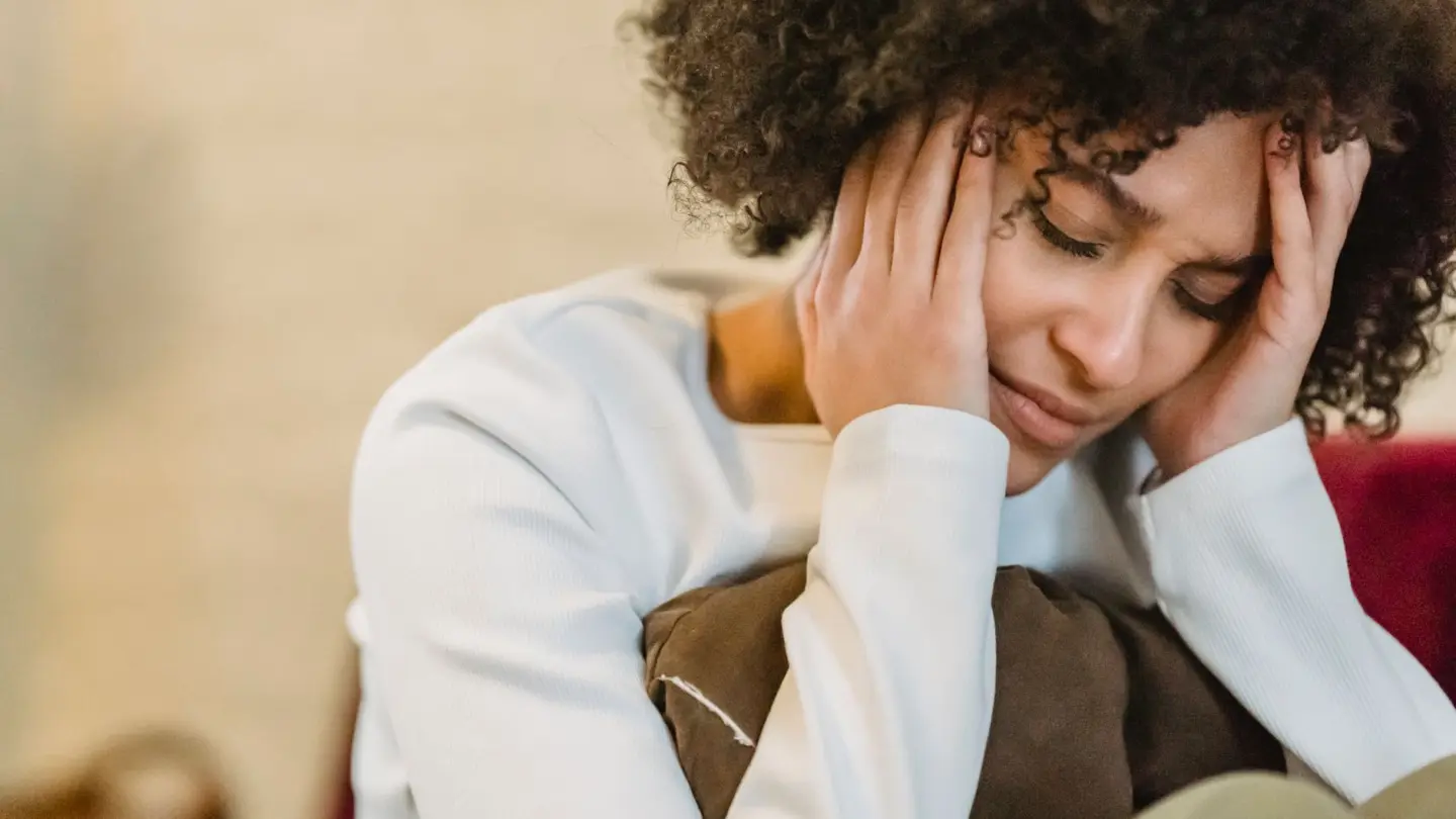 Natural remedies for depression and anxiety: frustrated African American female with closed eyes touching face while sitting