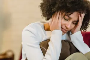 Natural remedies for depression and anxiety: frustrated African American female with closed eyes touching face while sitting