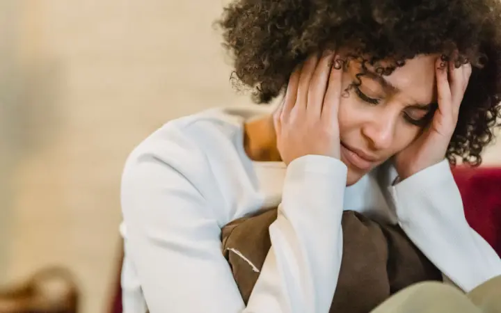 Natural remedies for depression and anxiety: frustrated African American female with closed eyes touching face while sitting