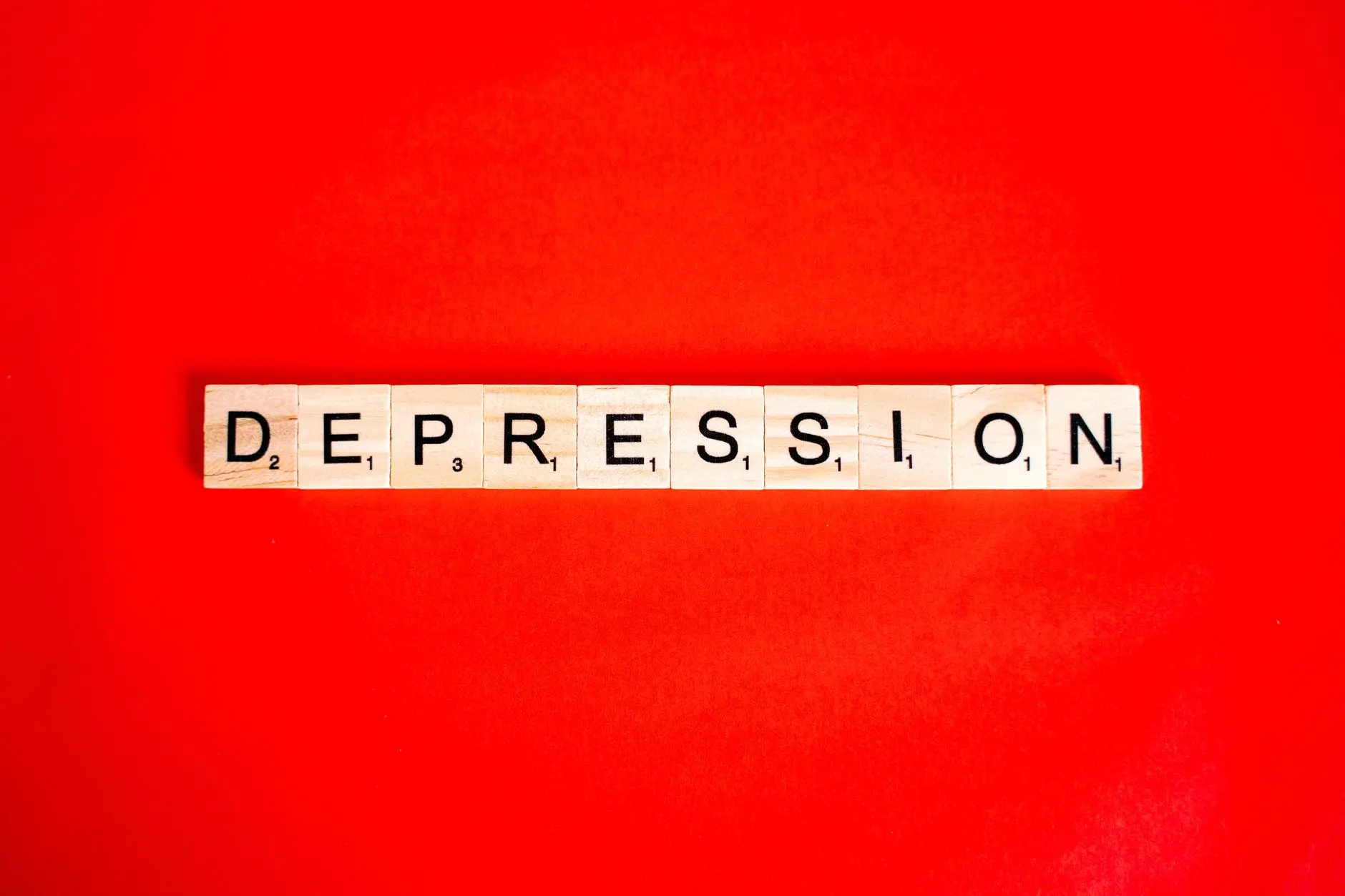 Word depression spelled with letter tiles on vibrant red background, highlighting mental health theme