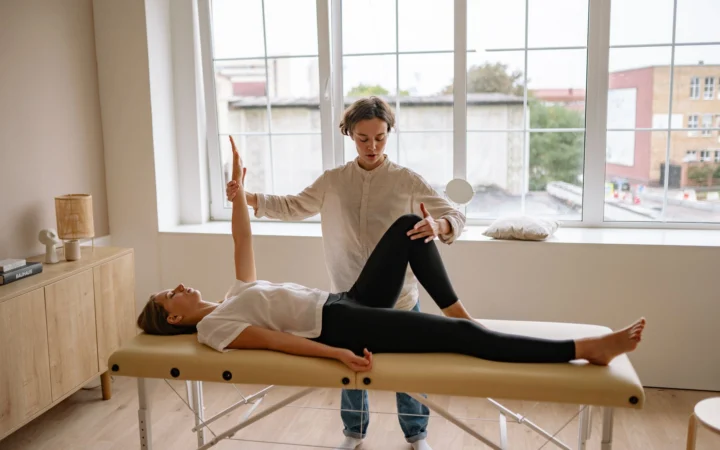 Specialist performs therapy on a woman lying on a massage table in a modern clinic setting.