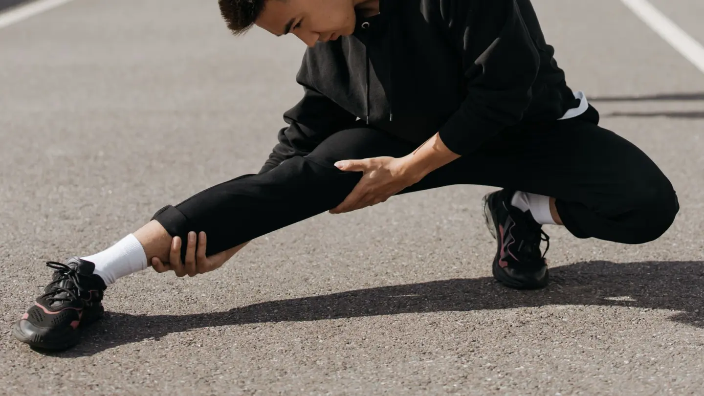 Sciatica stretch exercises: a young man performs stretching exercises on a city street, focusing on flexibility and fitness