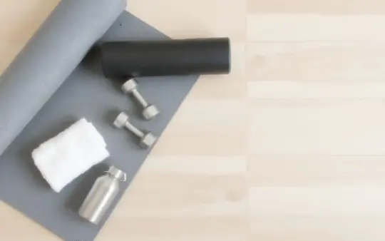 Seen from directly above on a light wooden floor, the objects spread evenly across the whole frame: a rolled grey yoga m, generated illustration