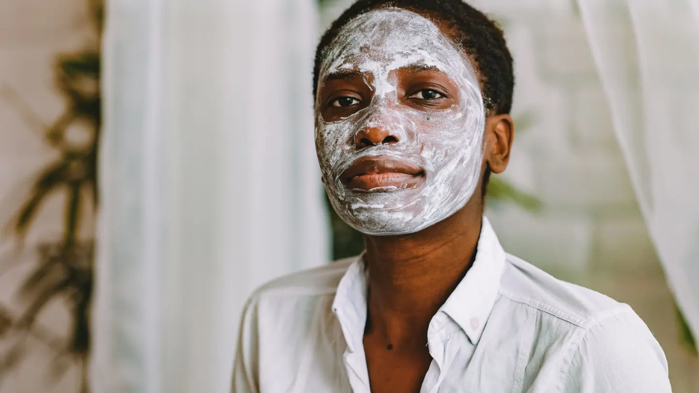 Skincare routine for black skin: portrait of a woman with a facial mask in a calm indoor setting, emphasizing skincare