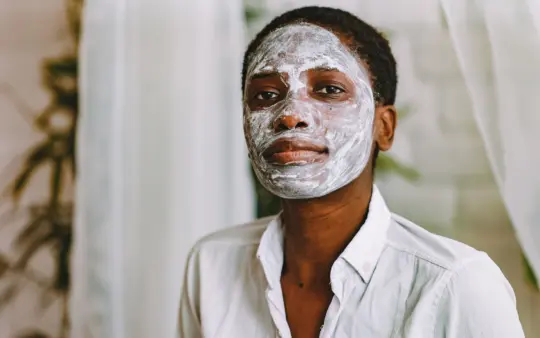 Skincare routine for black skin: a woman in a white shirt wearing a white clay face mask